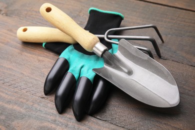 Photo of Claw gardening gloves, trowel and rake on wooden table