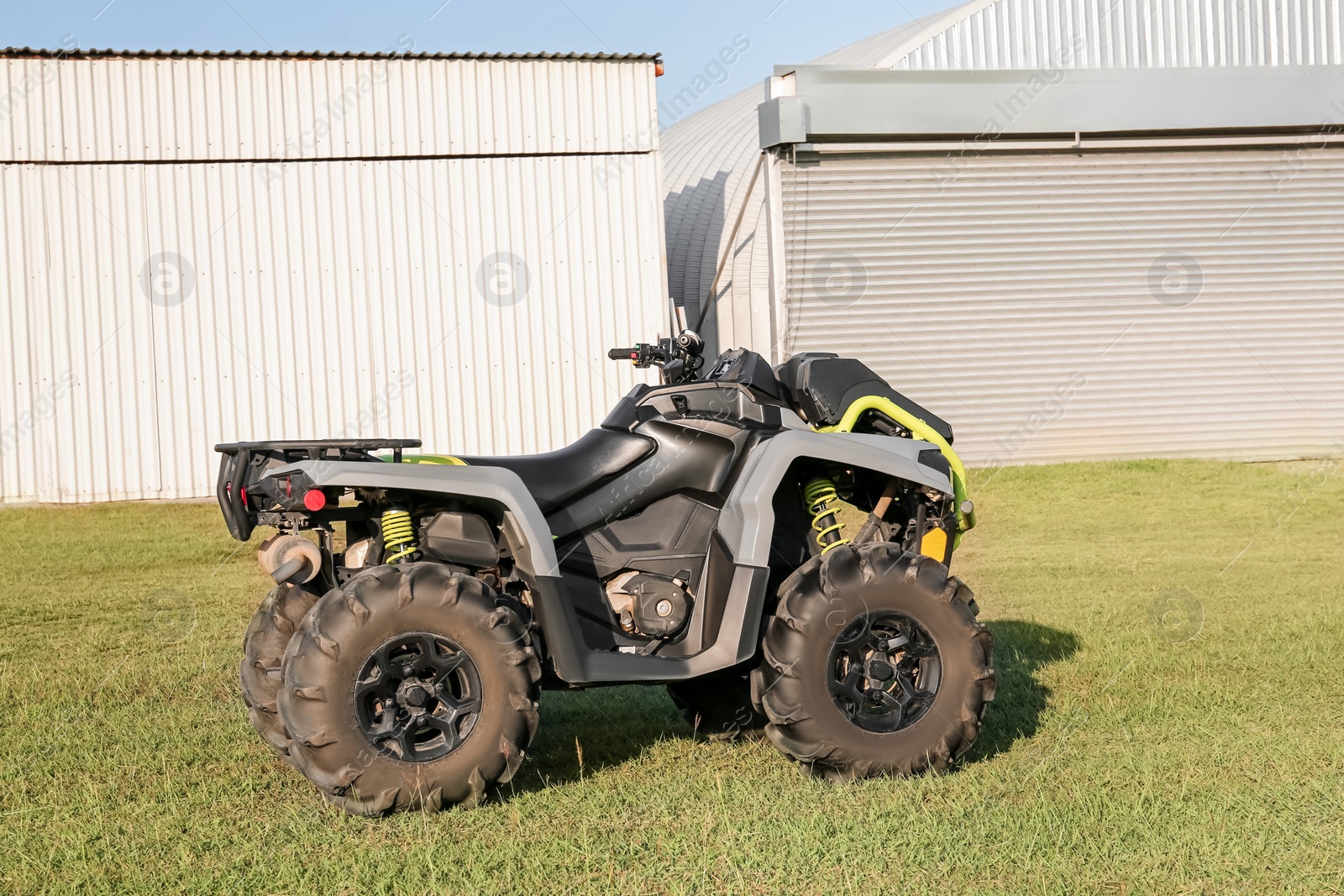 Photo of Modern quad bike in field near hangars on sunny day