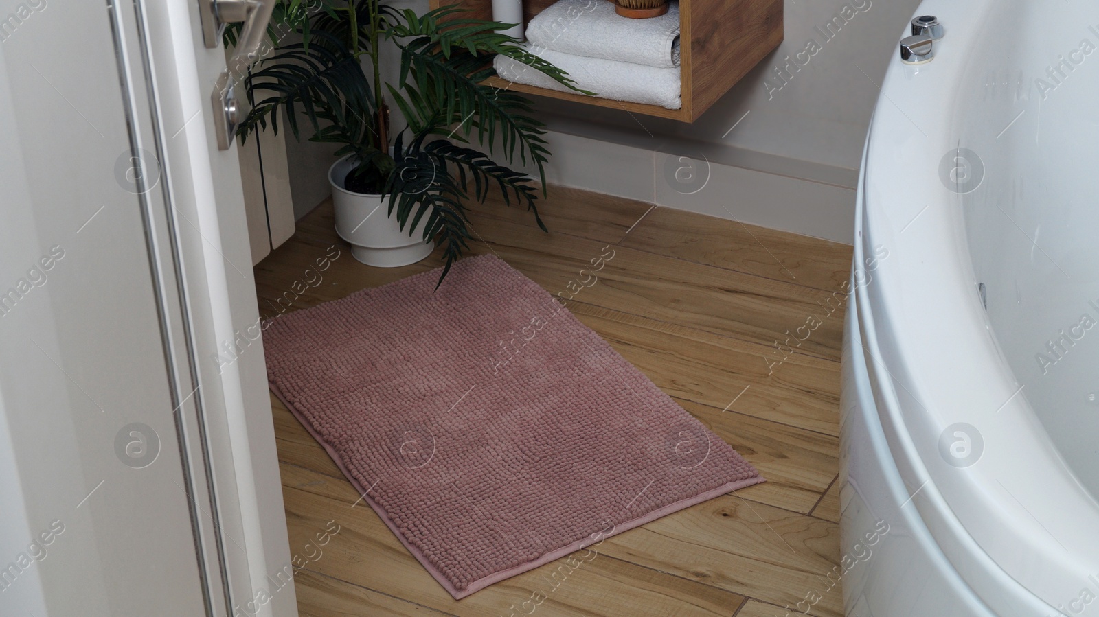 Photo of Soft bath mat on wooden floor in bathroom