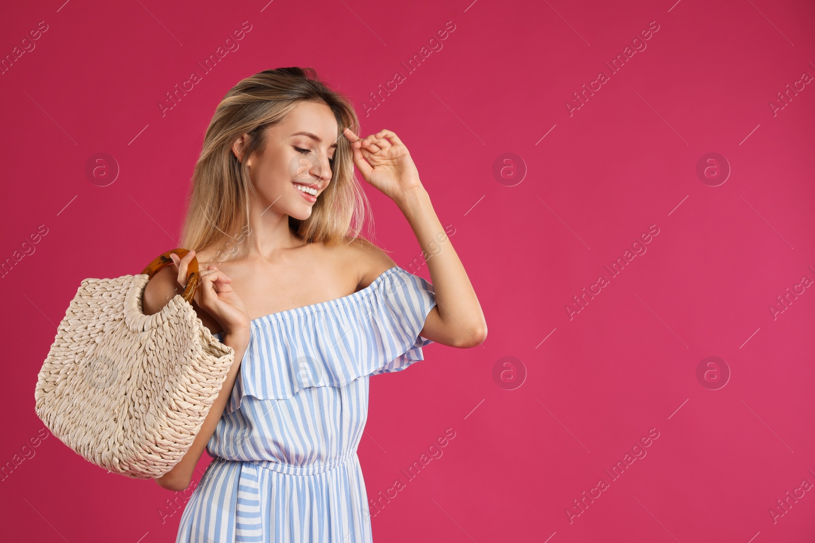 Photo of Beautiful young woman with stylish straw bag on pink background. Space for text