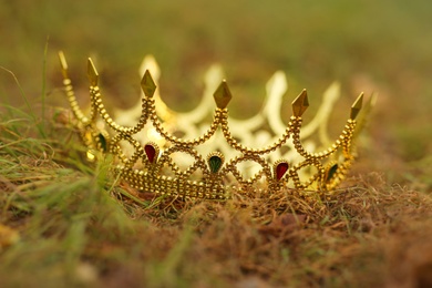 Photo of Beautiful golden crown on fresh green grass outdoors, closeup. Fantasy item