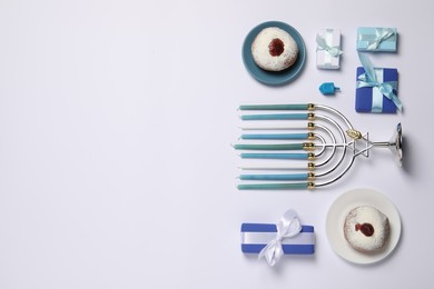 Flat lay composition with Hanukkah menorah and donuts on white background, space for text