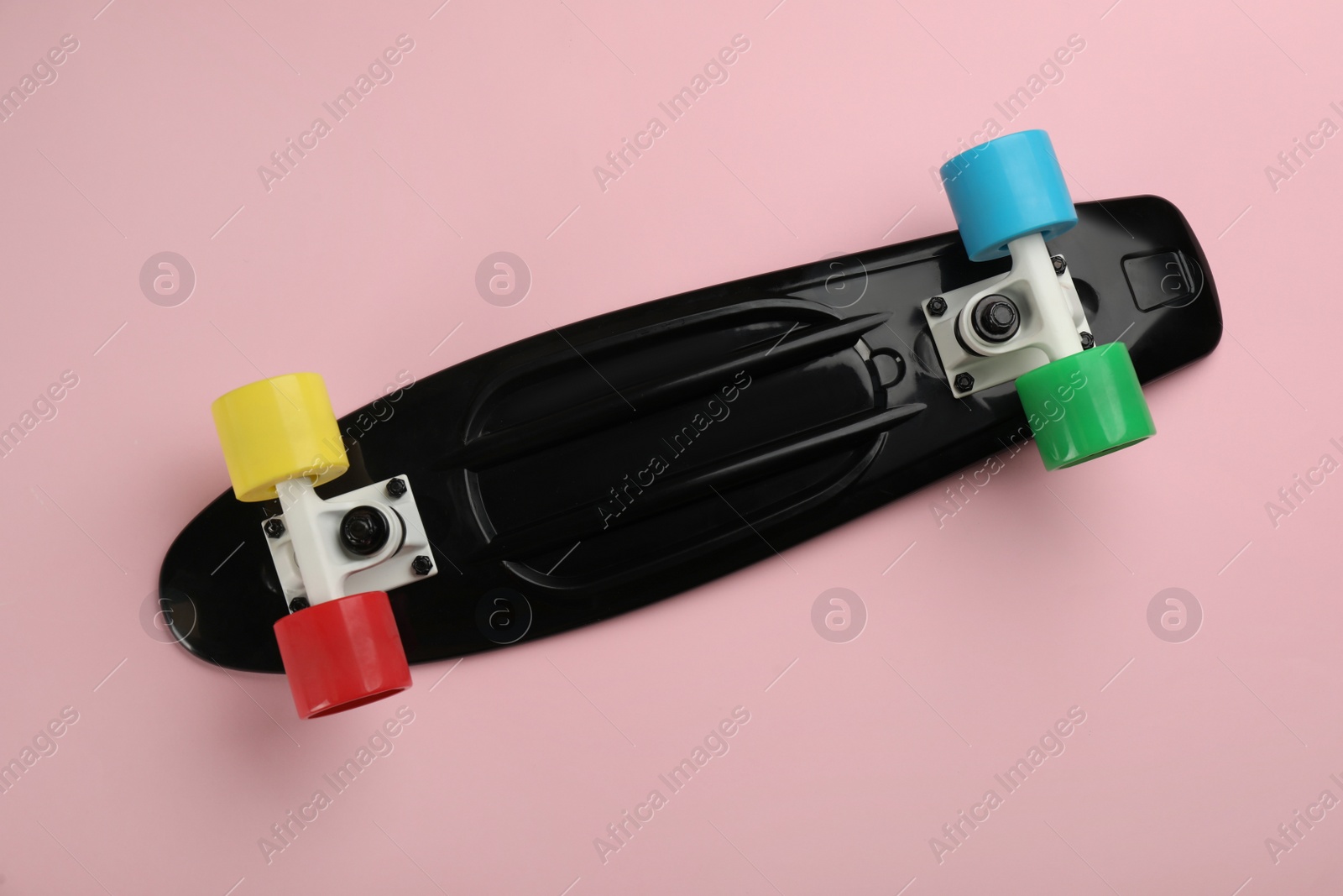 Photo of Black skateboard on pink background, top view