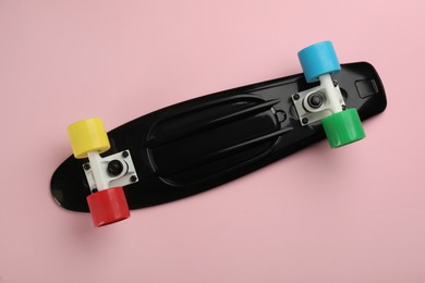 Photo of Black skateboard on pink background, top view