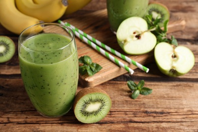 Photo of Delicious kiwi smoothie and fresh fruits on wooden table