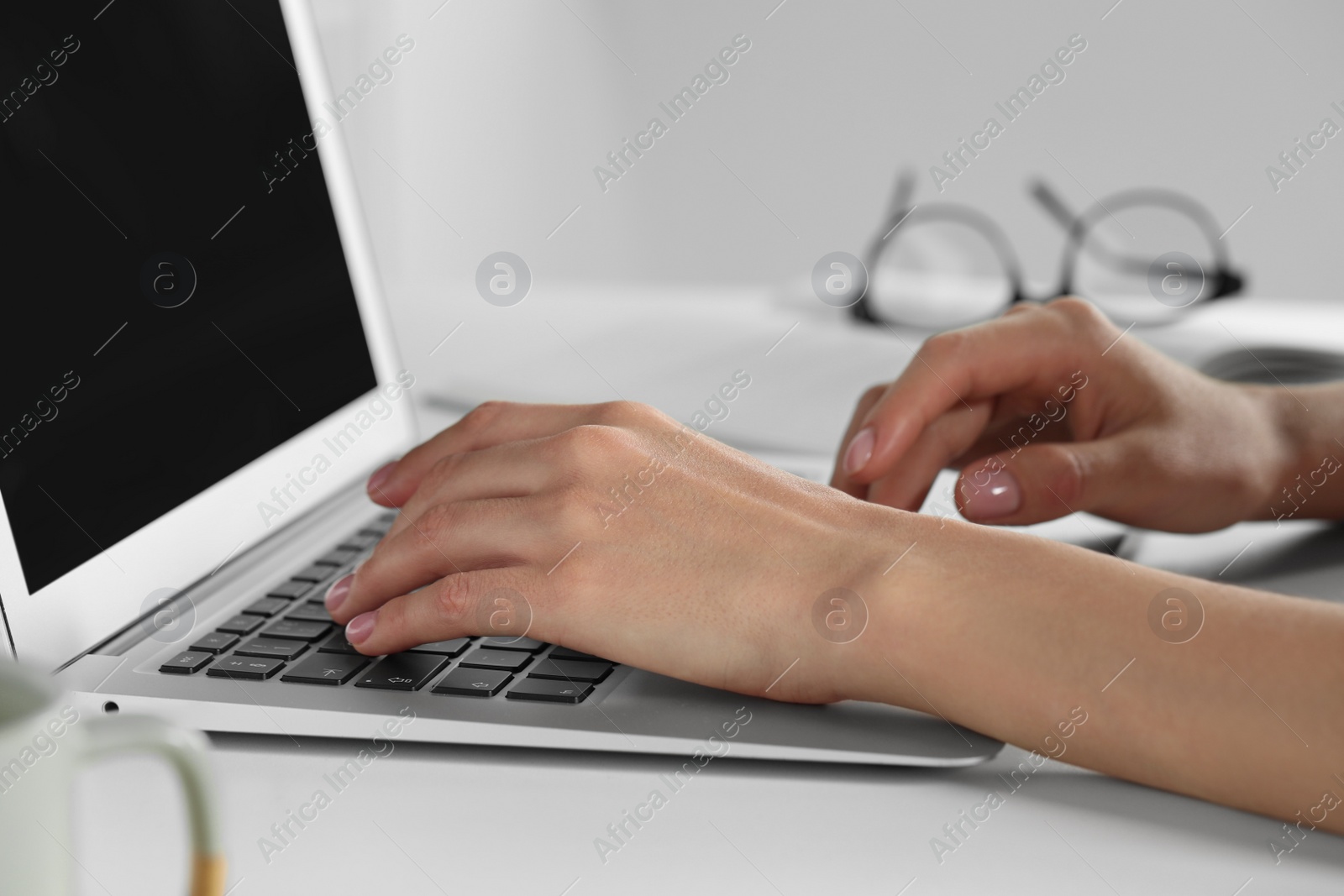 Photo of Young woman working with laptop at workplace, closeup