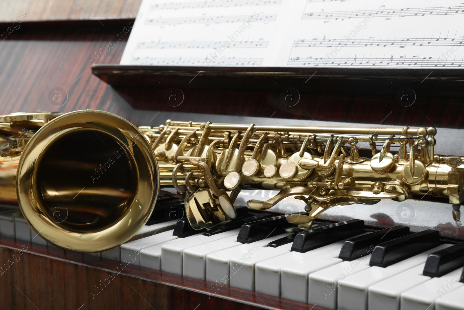 Photo of Beautiful saxophone on piano keys. Musical instruments