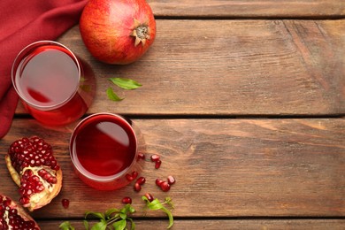 Photo of Tasty pomegranate juice in glasses and fresh fruits on wooden table, flat lay. Space for text
