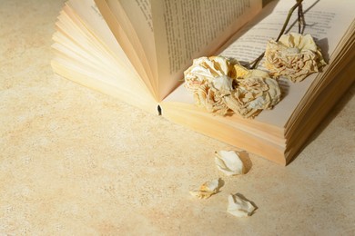 Photo of Book with beautiful dried flowers on light table, space for text