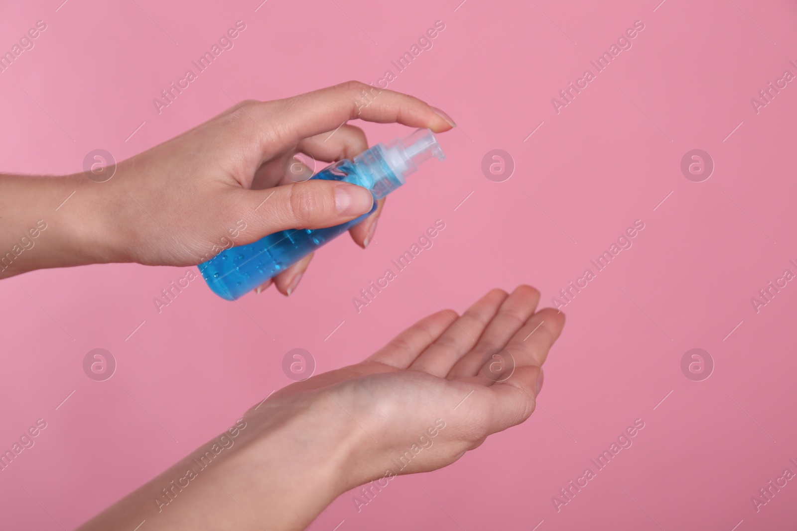 Photo of Woman applying antiseptic gel on pink background, closeup