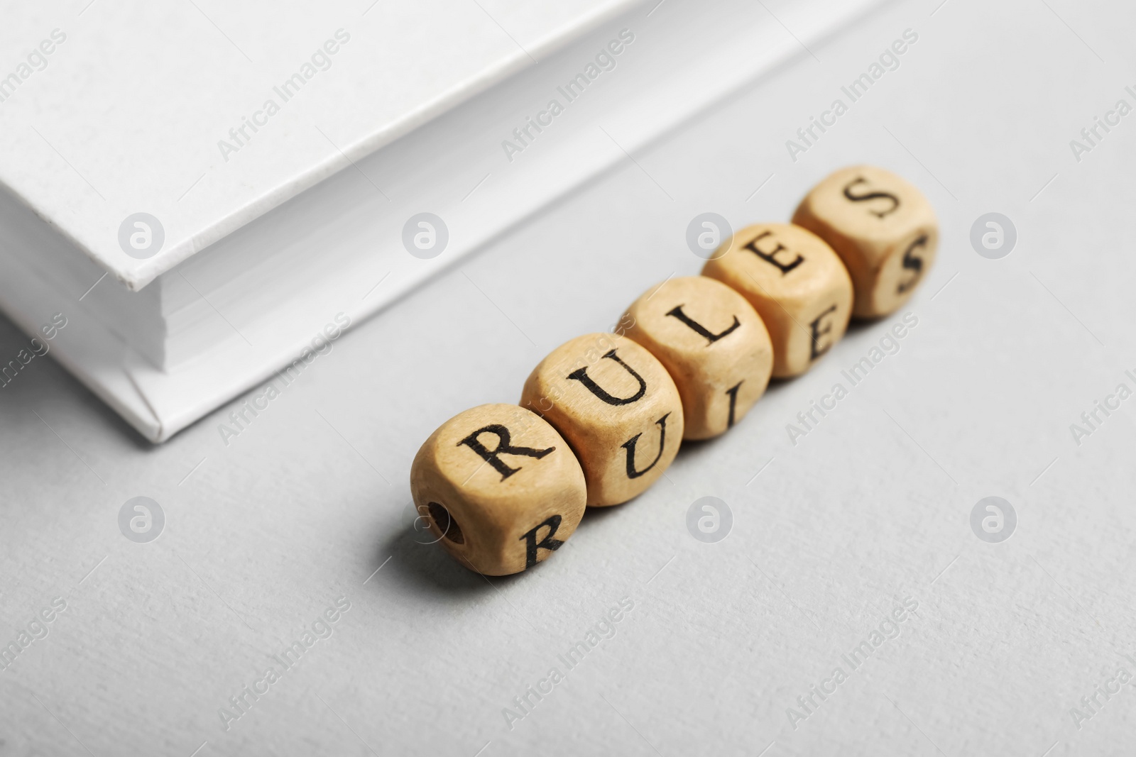 Photo of Word Rules made of wooden cubes with letters and book on white table