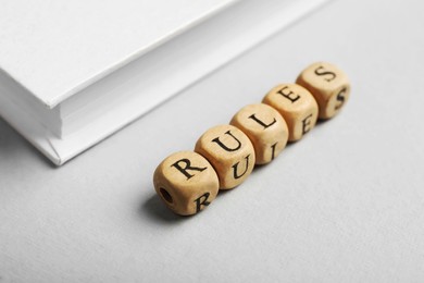 Photo of Word Rules made of wooden cubes with letters and book on white table