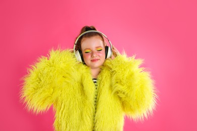 Photo of Cute indie girl with headphones on pink background