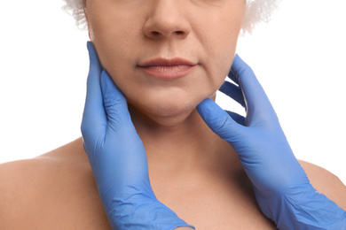 Photo of Doctor examining mature woman on white background, closeup. Double chin surgery
