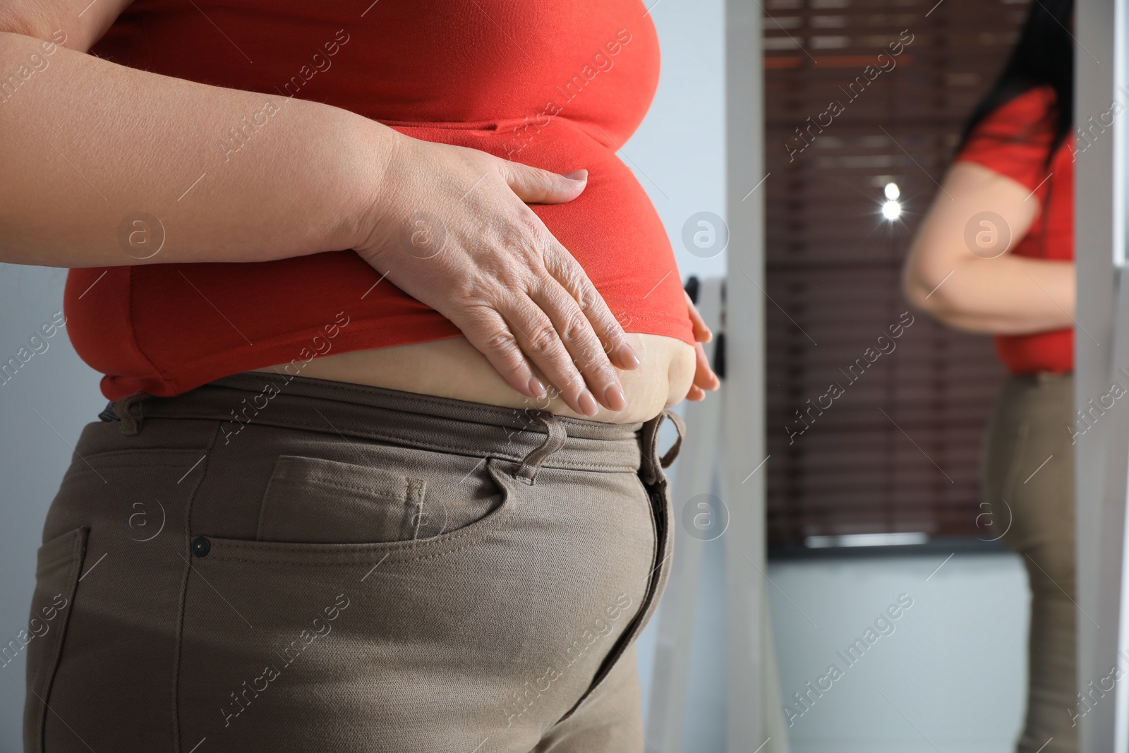 Photo of Overweight woman in tight shirt and trousers at home, closeup