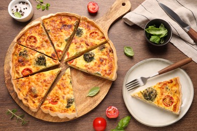 Photo of Delicious homemade vegetable quiche, ingredients and fork on wooden table, flat lay