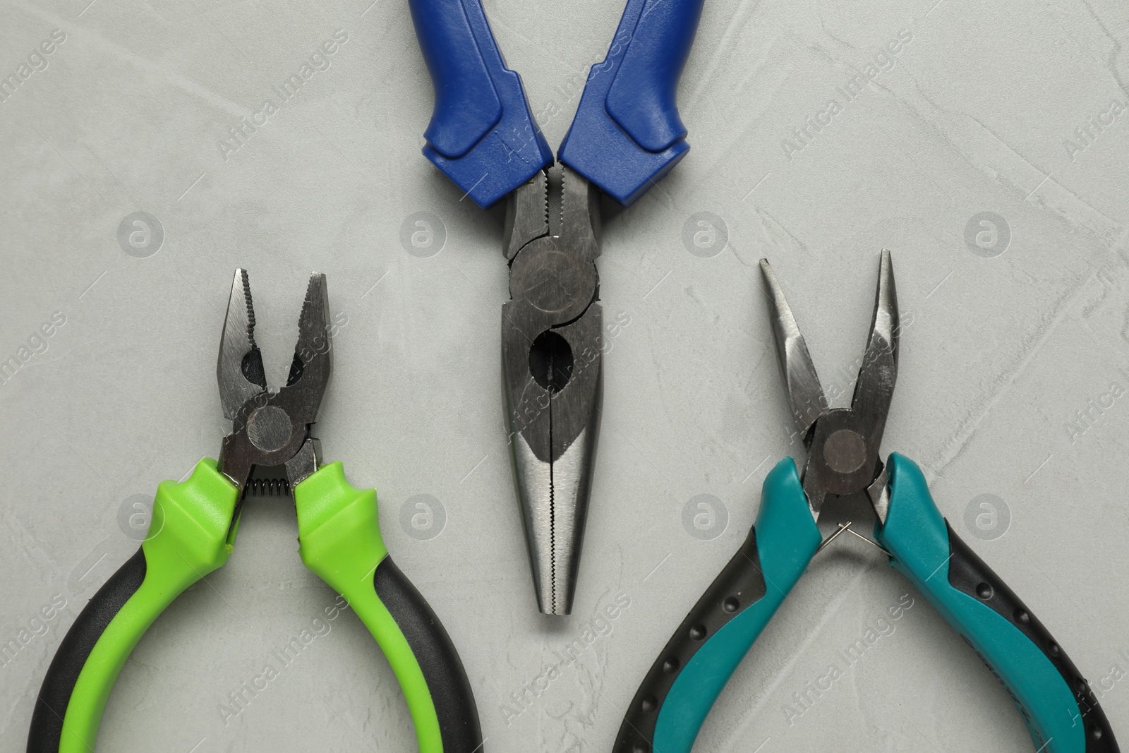 Photo of Different pliers on grey textured table, flat lay