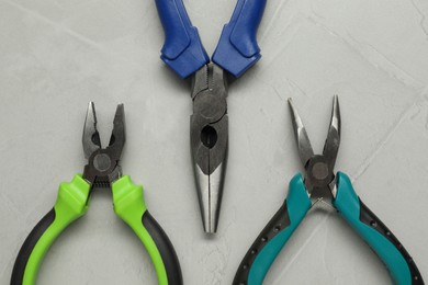 Different pliers on grey textured table, flat lay