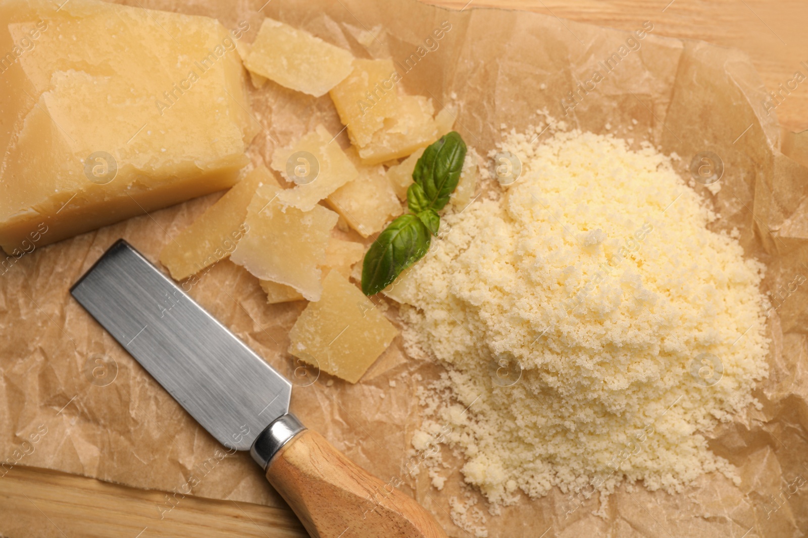 Photo of Delicious parmesan cheese on parchment paper, flat lay