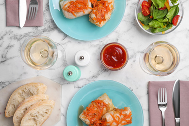 Delicious cabbage rolls served on white marble table, flat lay