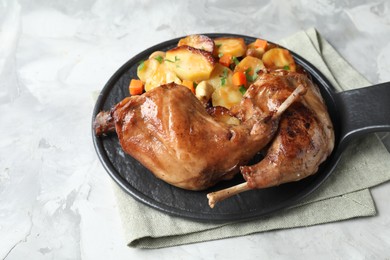 Tasty cooked rabbit meat with vegetables on light grey table