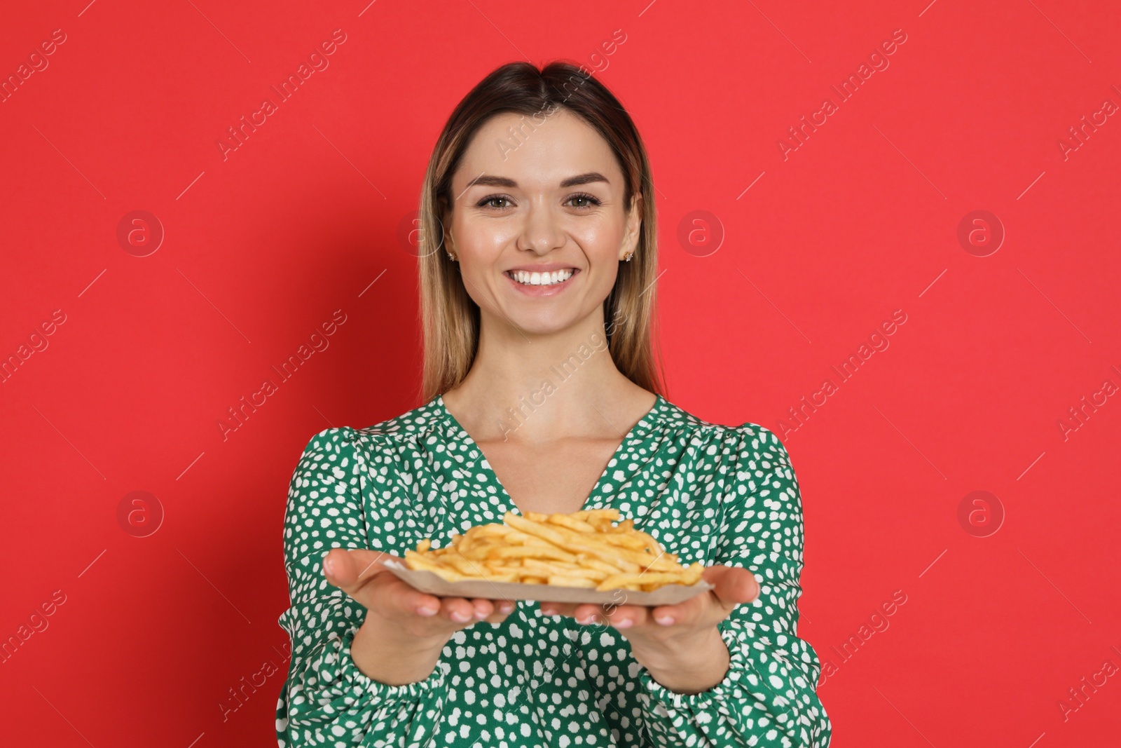 Photo of Young woman with French fries on red background