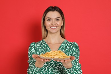 Young woman with French fries on red background