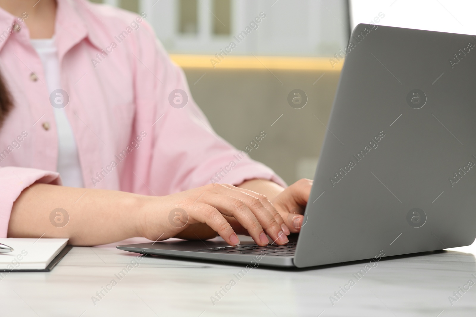 Photo of Woman using laptop at white table indoors, closeup