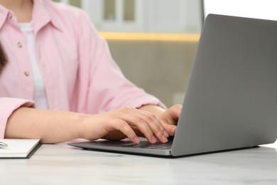 Photo of Woman using laptop at white table indoors, closeup