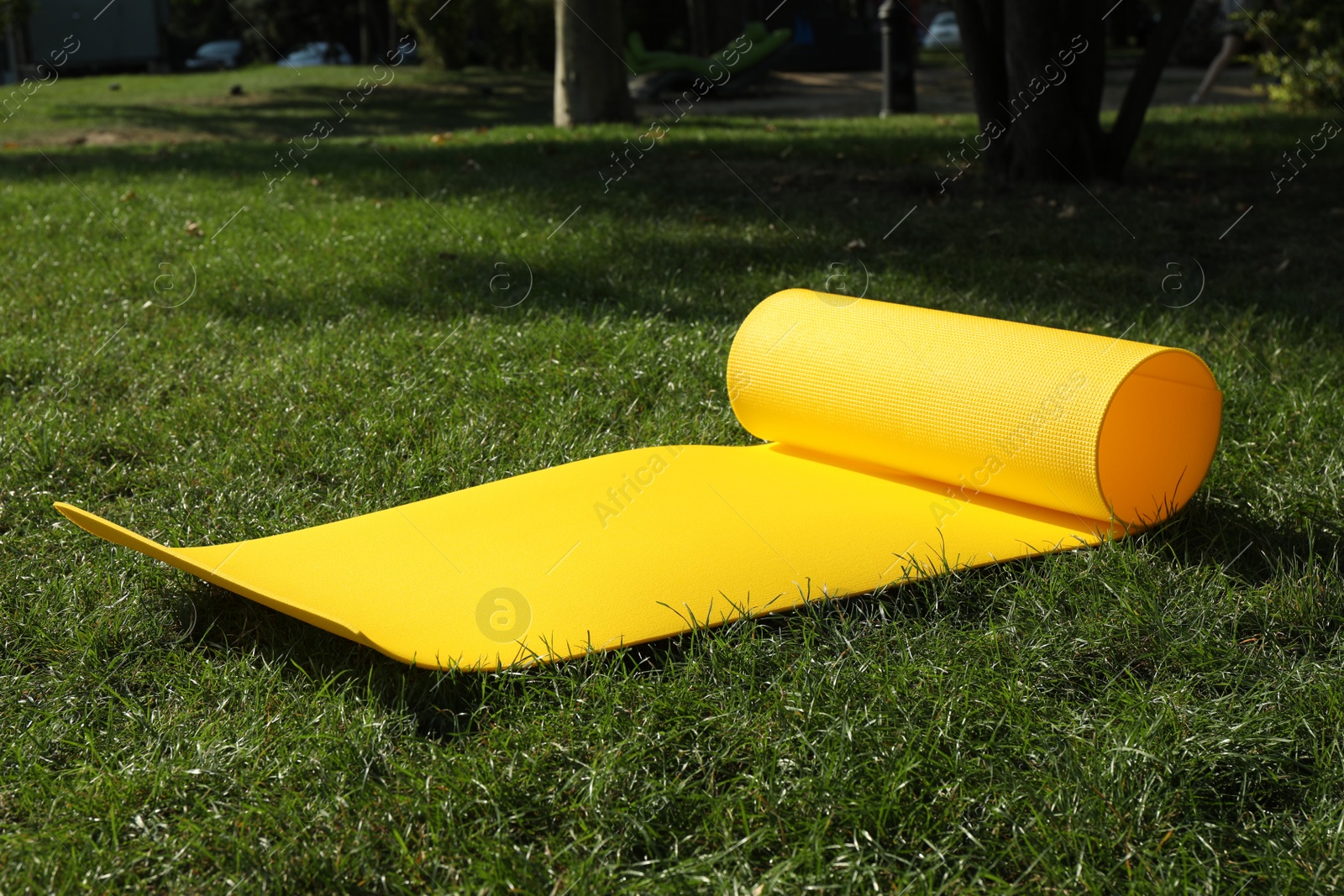 Photo of Bright exercise mat on fresh green grass outdoors