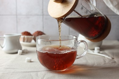 Photo of Pouring warm tea into cup on light table, closeup