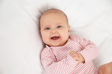 Photo of Cute little baby lying on white fabric, above view