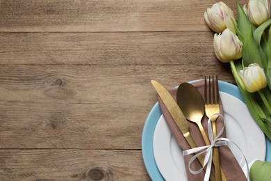 Photo of Stylish table setting with cutlery and tulips on wooden background, flat lay. Space for text