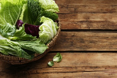 Photo of Many different cabbage leaves on wooden table, space for text