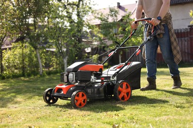 Man cutting green grass with lawn mower in garden, closeup