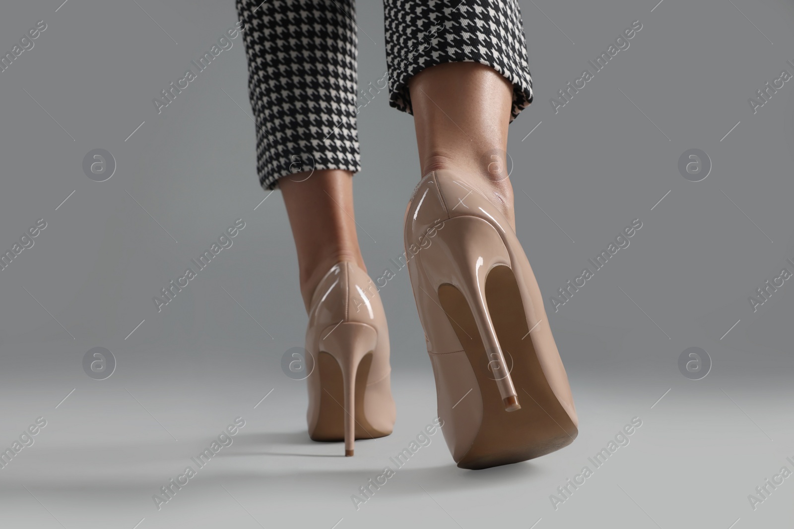 Photo of Businesswoman in beige shoes on grey background, closeup