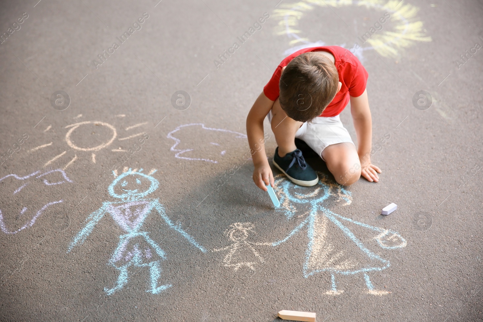 Photo of Little child drawing family with chalk on asphalt