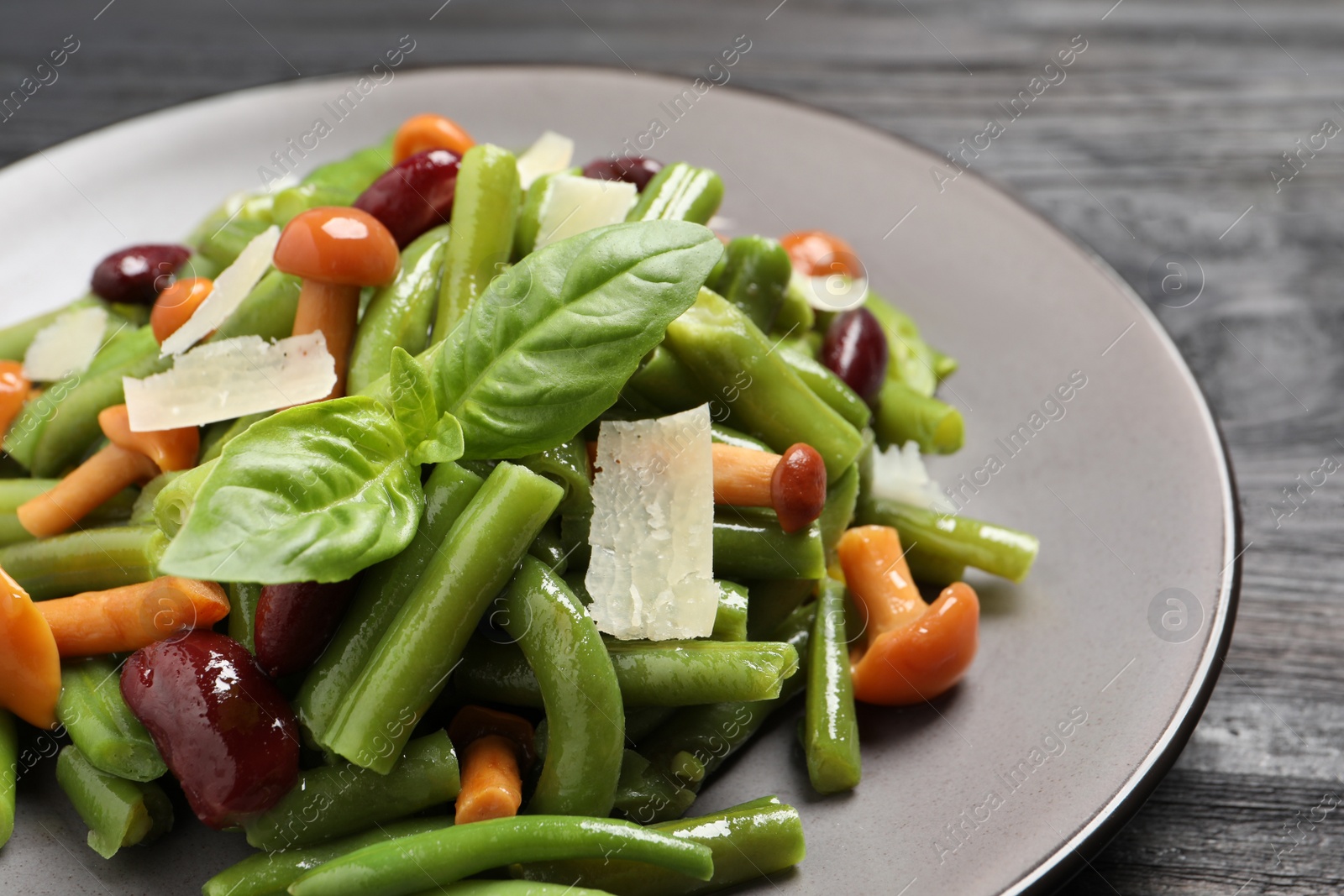 Photo of Delicious salad with green beans, mushrooms and cheese on black wooden table, closeup