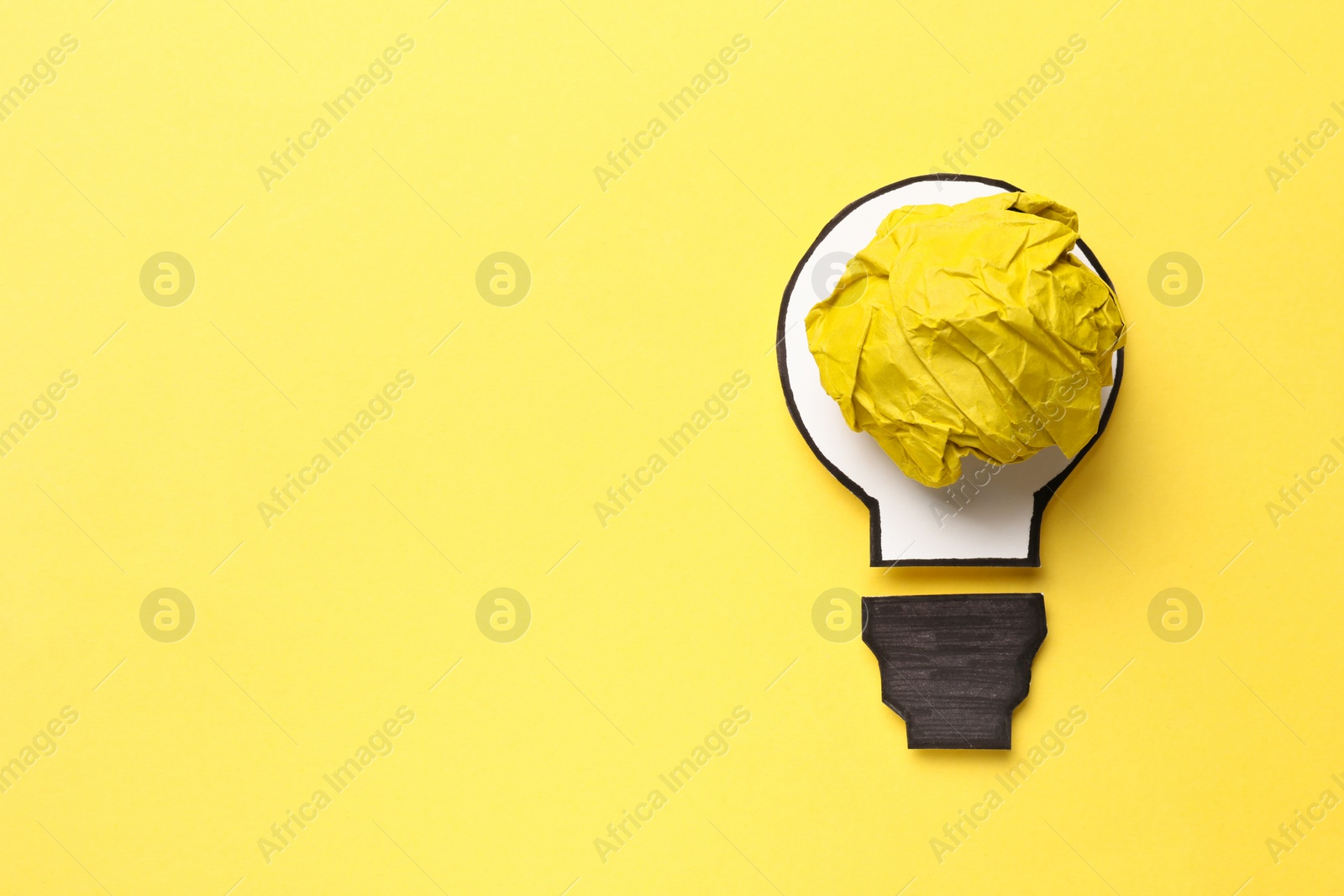 Photo of Idea concept. Light bulb made with crumpled paper and drawing on yellow background, top view. Space for text