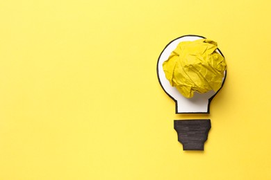 Photo of Idea concept. Light bulb made with crumpled paper and drawing on yellow background, top view. Space for text