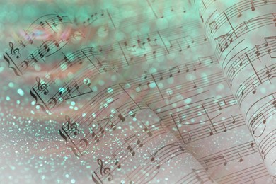 Double exposure of sheets with music notes and green glitter as background, bokeh effect