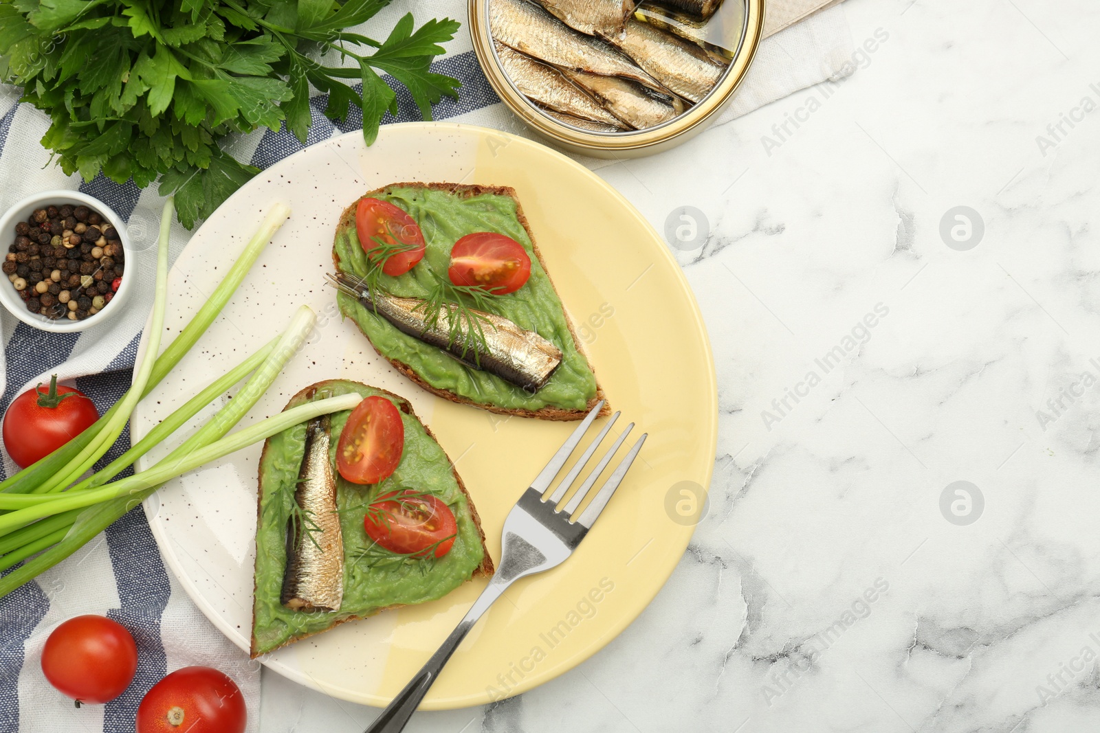 Delicious sandwiches with sprats, tomatoes, avocado puree and dill served on white marble table, flat lay. Space for text Photo of Delicious sandwiches with sprats, tomatoes, avocado puree and dill served on white marble table, flat lay. Space for text