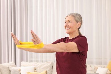 Senior woman doing exercise with fitness elastic band at home