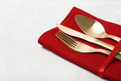 Photo of Napkin with golden cutlery on table, closeup. Space for text