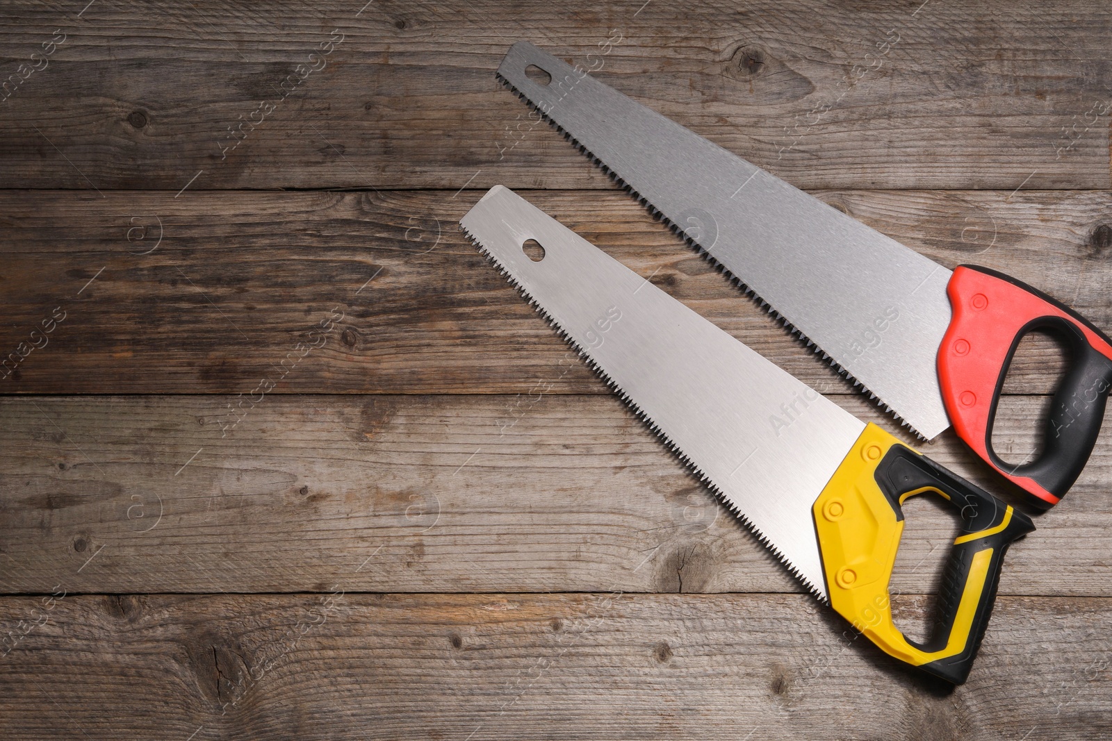 Photo of Saws with colorful handles on wooden background, flat lay. Space for text