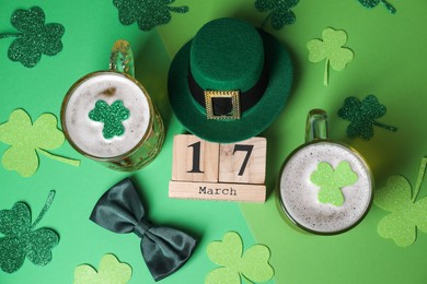 Photo of St. Patrick's day party on March 17. Green beer, leprechaun hat, bowtie, wooden block calendar and decorative clover leaves on green background, flat lay