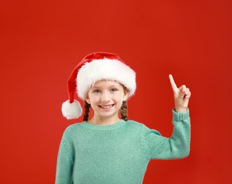 Image of Happy little child in Santa hat on red background. Christmas celebration