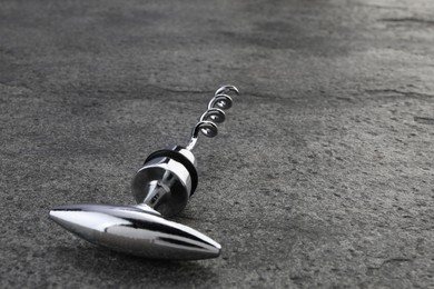 One metal corkscrew on grey textured table, closeup. Space for text