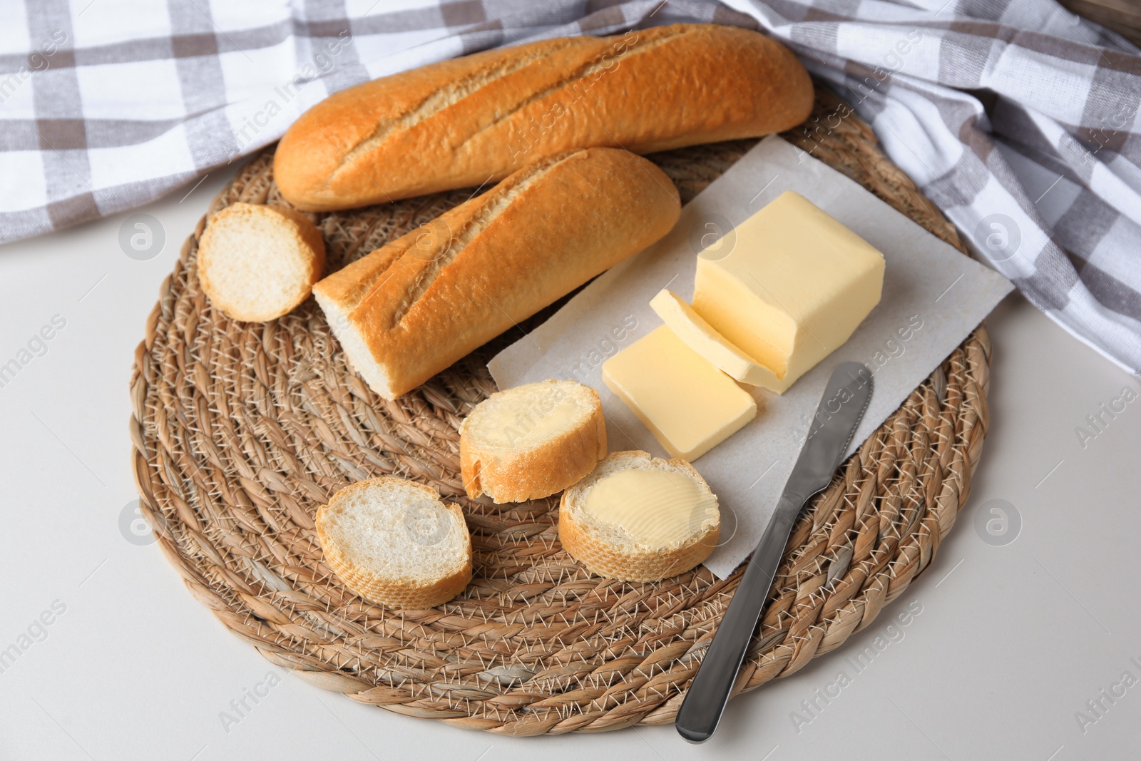 Photo of Tasty cut baguette with fresh butter on white table