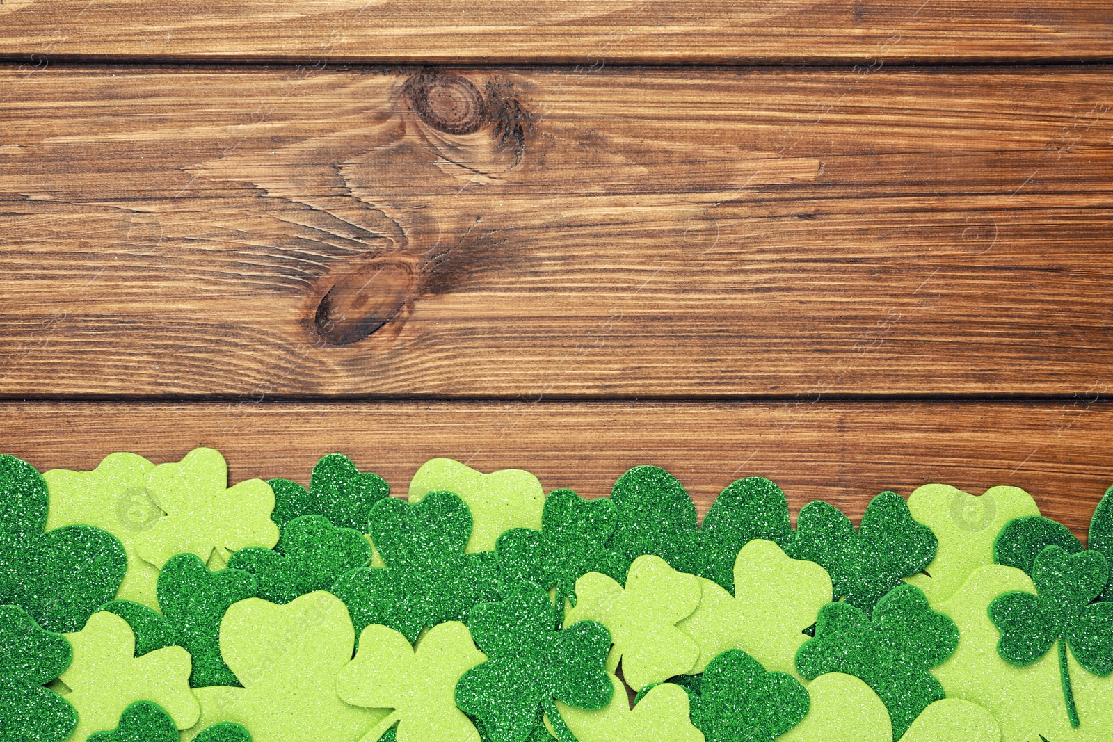 Photo of Decorative clover leaves on wooden background, flat lay with space for text. St. Patrick's Day celebration